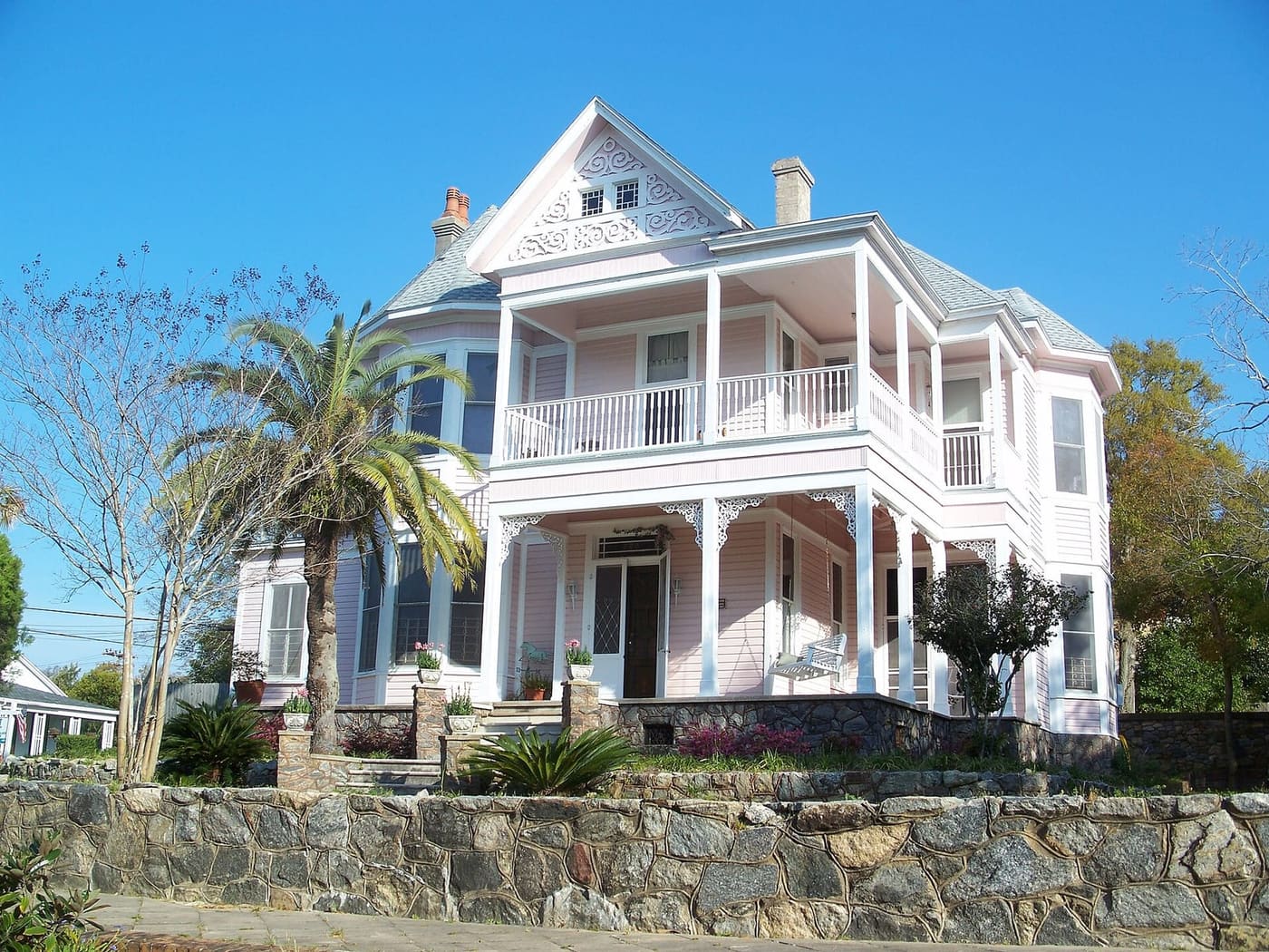 Two-story Victorian house with wraparound porches and palm trees in Pensacola North Hill