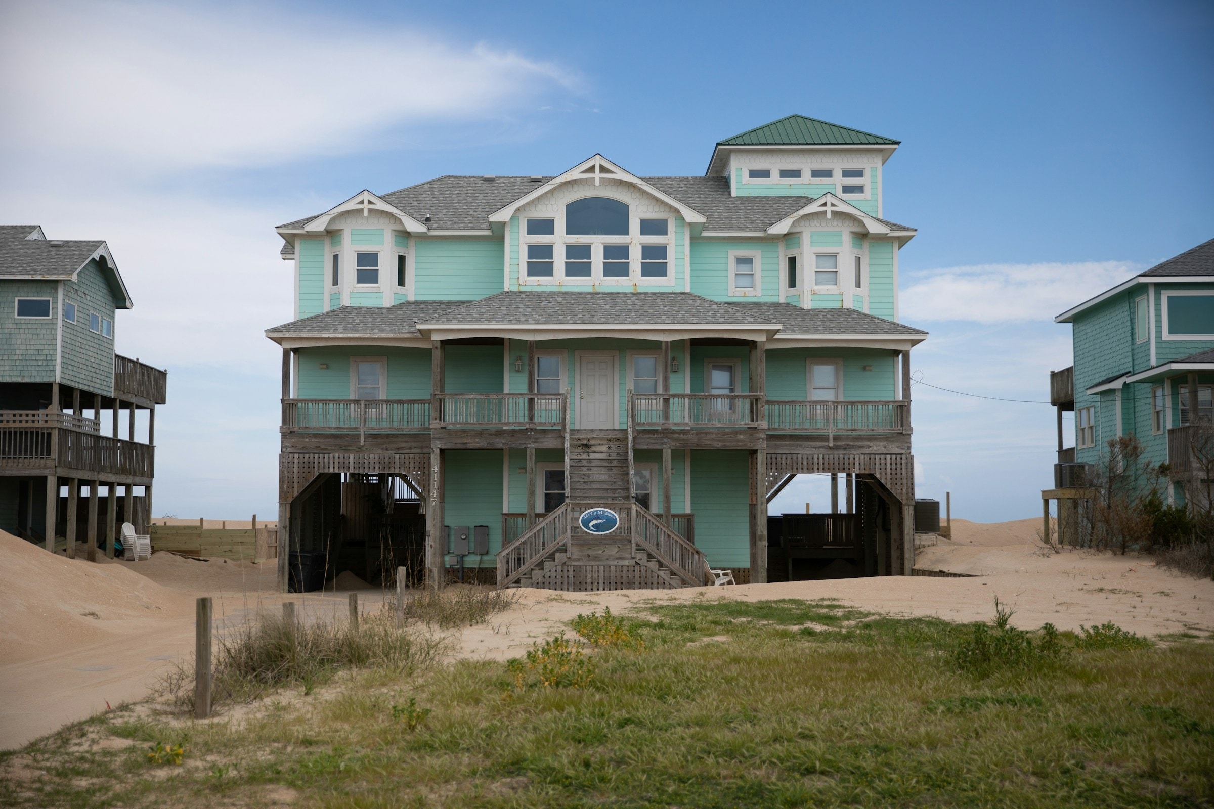 A substantial mint-colored beach house with balconies, gables and a tower. Illustrative architecture, not a current listing.