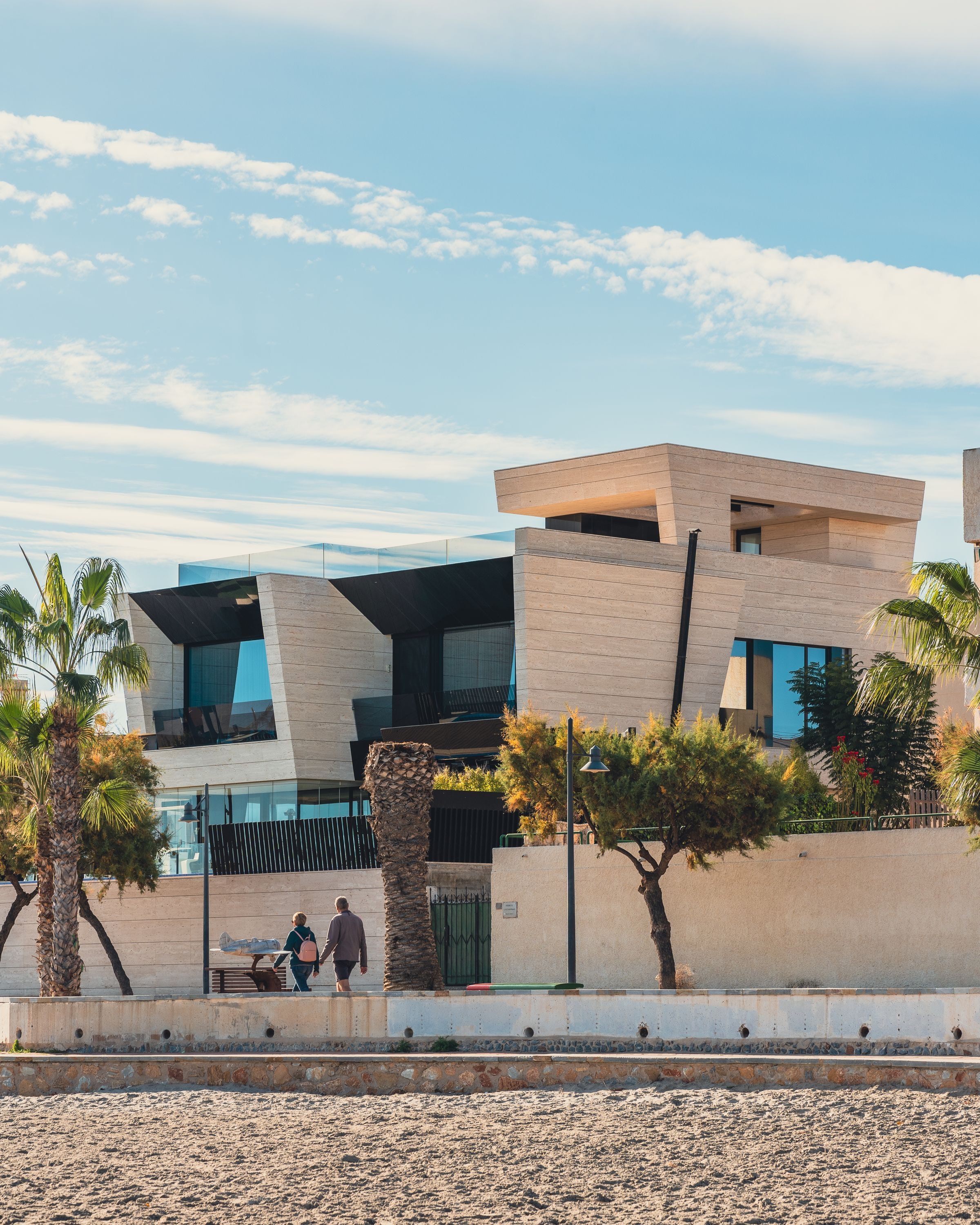 Contemporary beachfront architecture with stone, glass and palms. Illustrative architecture, not a current listing.